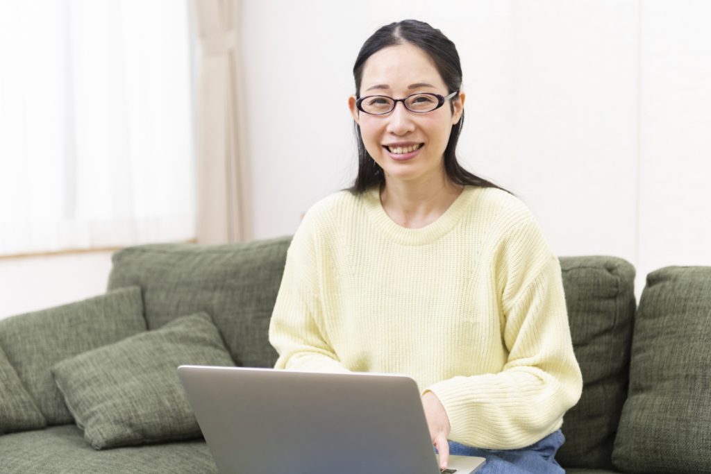 パソコンを触っている、眼鏡をかけた笑顔の女性