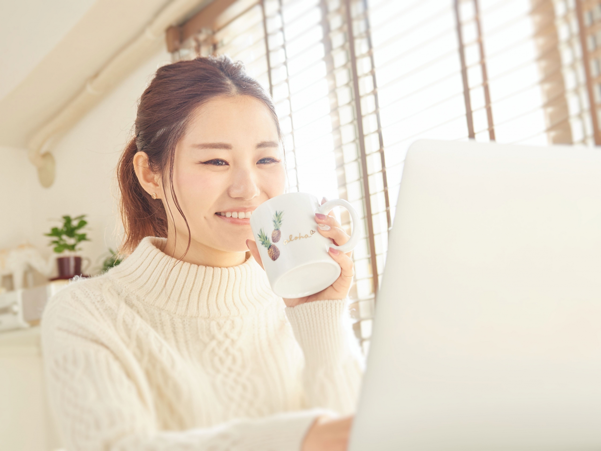 お茶を飲みながらパソコンをする女性の写真